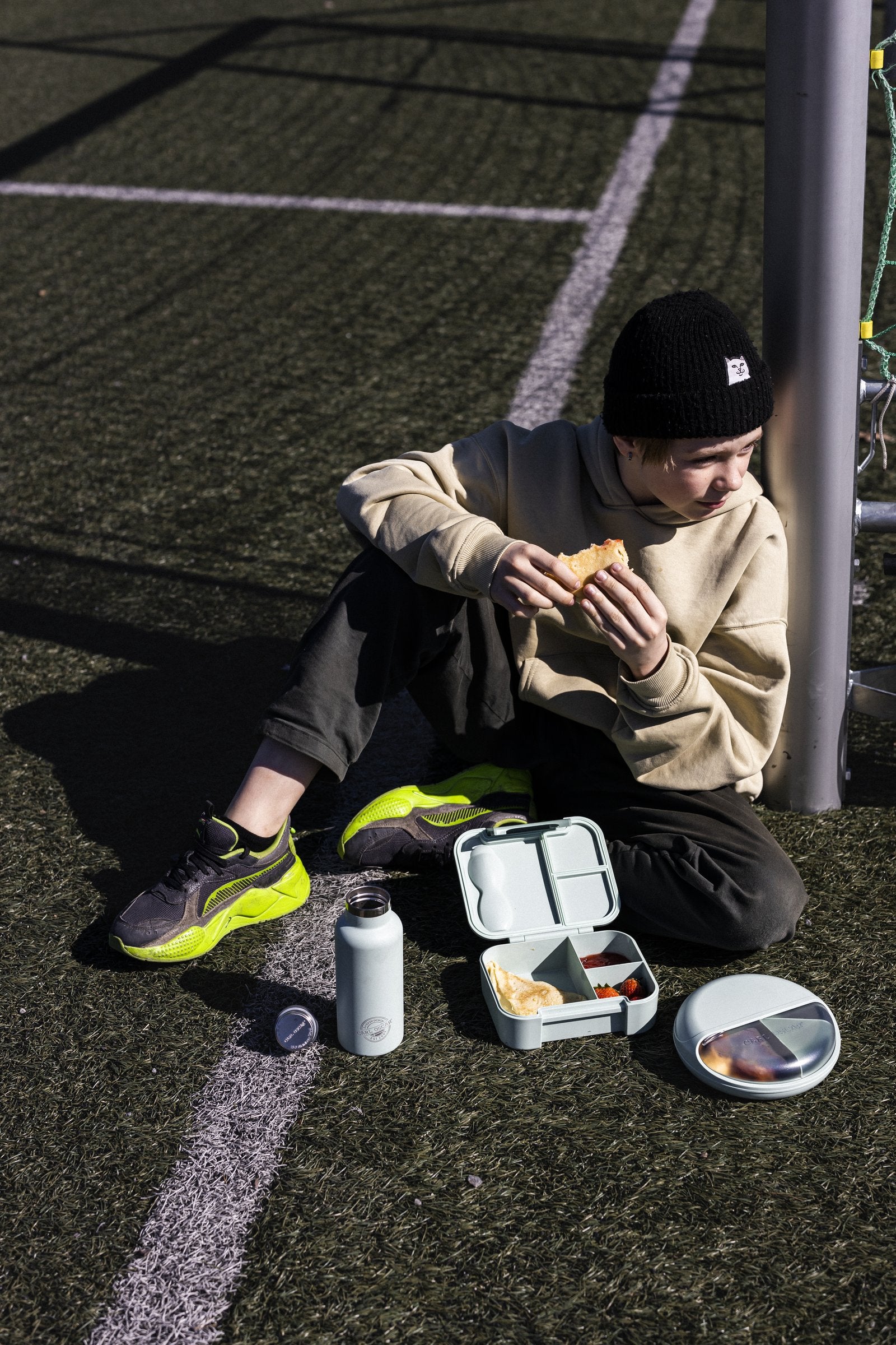 Niño en cancha con lonchera, termo y SnackDisc Carl Oscar — productos disponibles en Mamá Porqué Chile