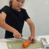 Niña cortando una zanahoria cruda con el cuchillo KiddiKutter